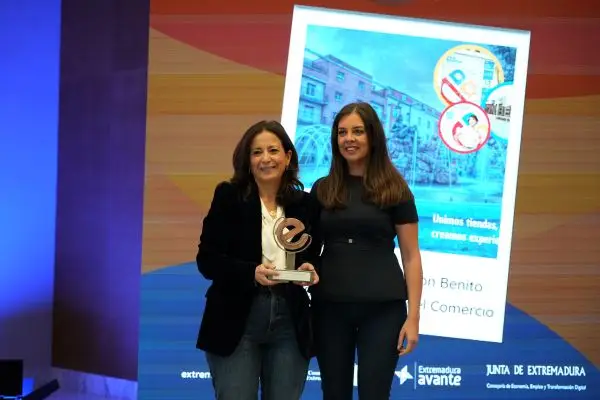 Dos mujeres sostienen premio en evento oficial