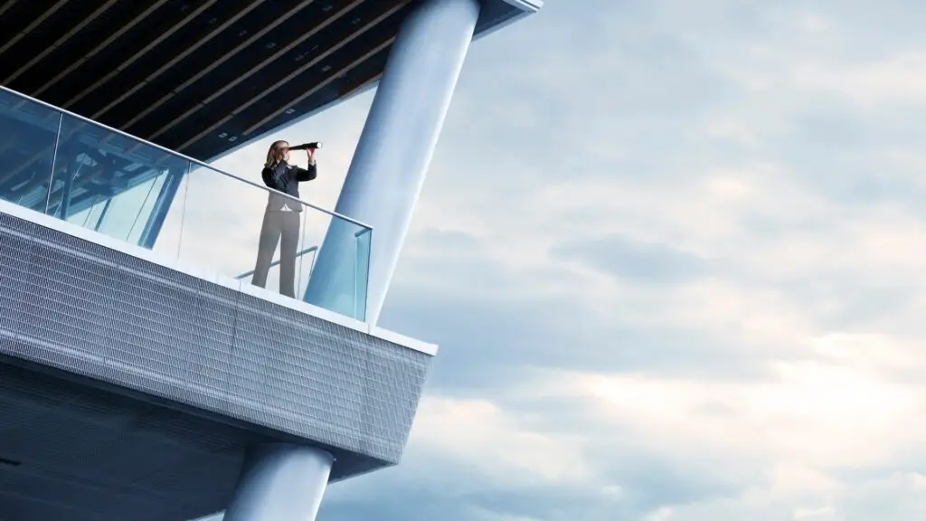 Mujer ejecutiva mirando con telescopio desde edificio moderno