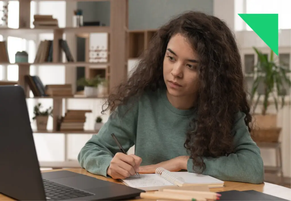 Joven estudiando con portátil y cuaderno en casa