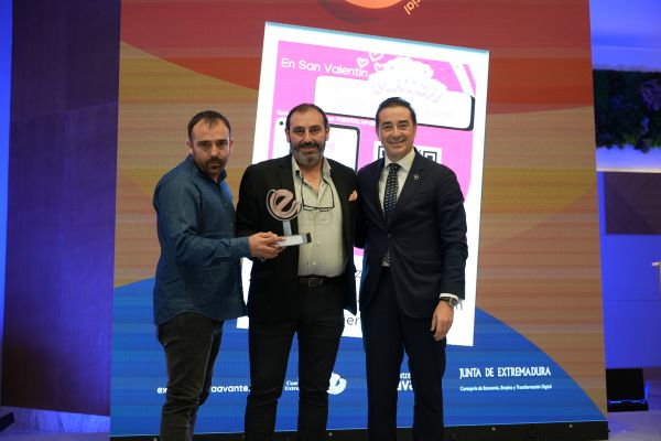 Tres hombres sostienen premio en escenario oficial