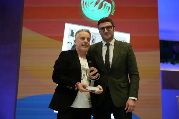 Dos hombres sostienen premio en escenario