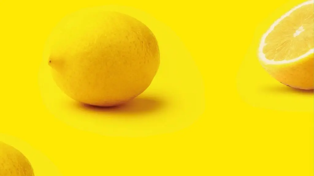 Limón entero y medio limón sobre fondo amarillo
