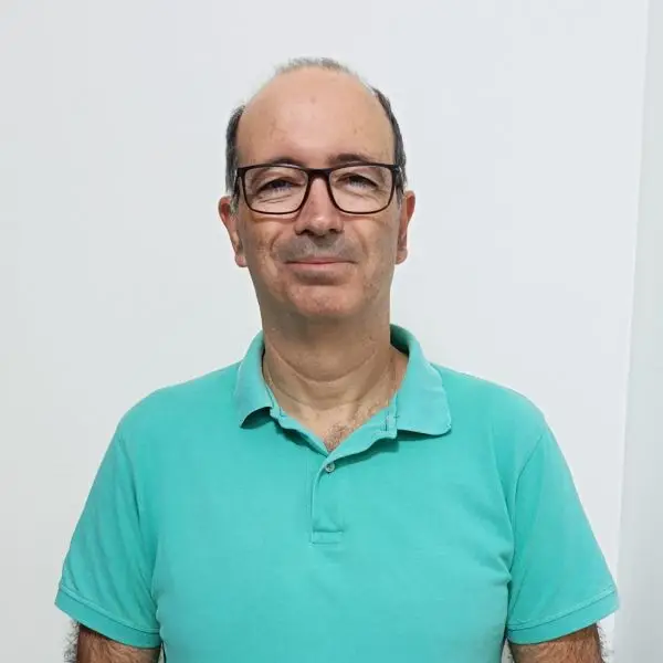 Hombre con gafas y polo turquesa sobre fondo blanco