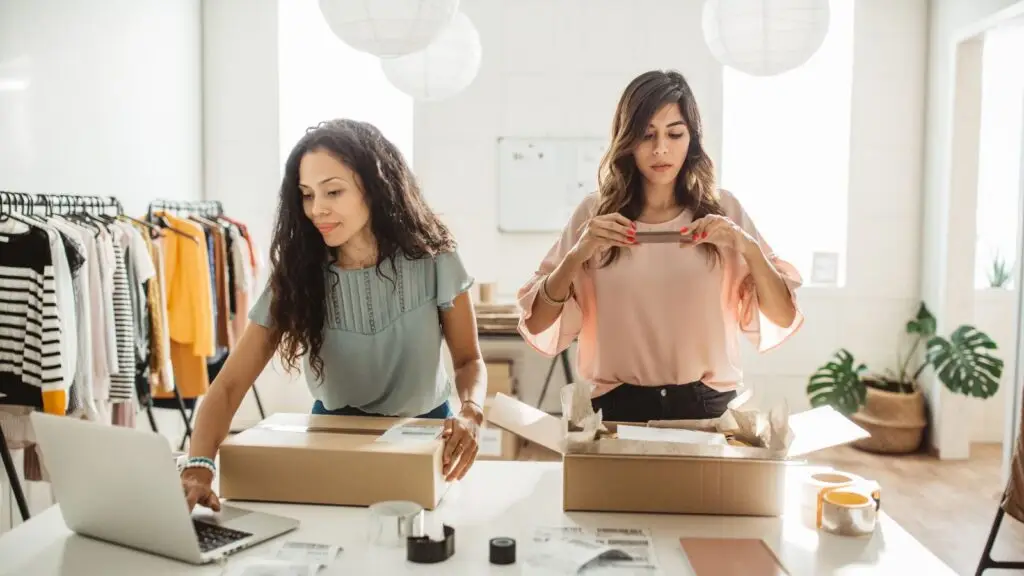 Dos mujeres preparando paquetes en una tienda de ropa
